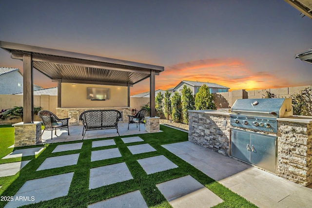 patio terrace at dusk with an outdoor living space, grilling area, and exterior kitchen