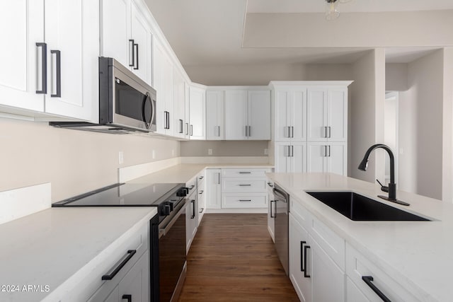 kitchen with appliances with stainless steel finishes, white cabinets, sink, and dark wood-type flooring