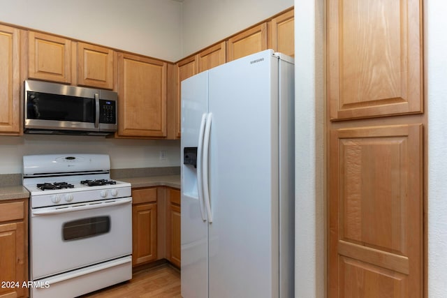 kitchen with white appliances and light hardwood / wood-style flooring