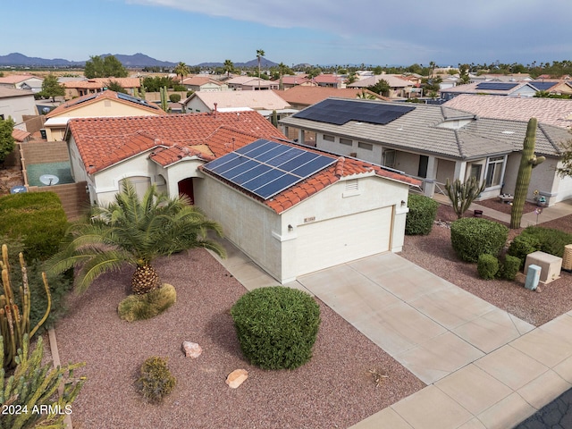 mediterranean / spanish-style home with a mountain view, solar panels, and a garage