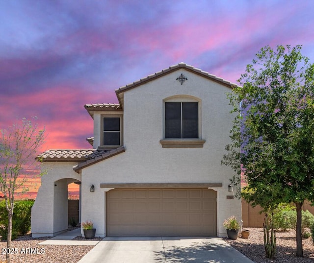 19561 W Woodlands Ave, Buckeye, AZ 85326 - mediterranean / spanish-style home featuring concrete driveway, a tile roof, an attached garage, and stucco siding