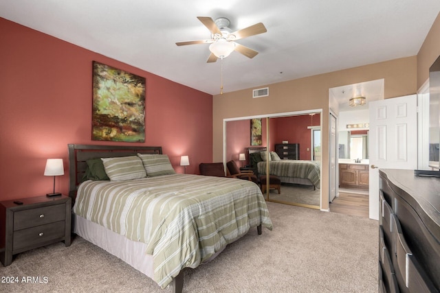 bedroom with light carpet, ensuite bath, and ceiling fan