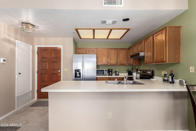 kitchen with sink, appliances with stainless steel finishes, kitchen peninsula, and a textured ceiling