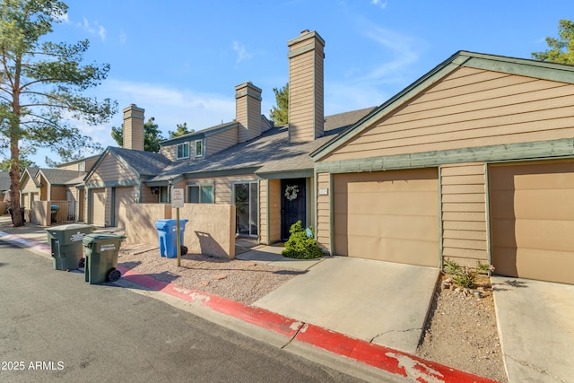 multi unit property featuring driveway, a chimney, a garage, and fence