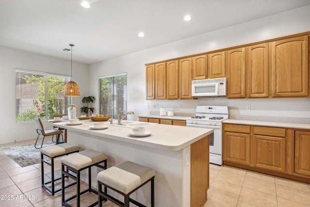 35402 N 32nd Dr, Phoenix, AZ 85086 - kitchen with white appliances, a breakfast bar area, light tile patterned floors, light countertops, and recessed lighting