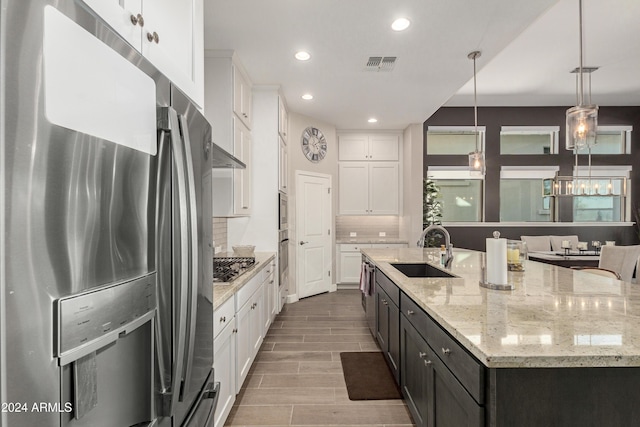 kitchen featuring pendant lighting, a center island with sink, sink, appliances with stainless steel finishes, and white cabinetry