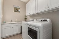 laundry area featuring cabinets, light wood-type flooring, washer and clothes dryer, and sink