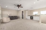 unfurnished living room featuring light carpet and ceiling fan