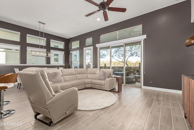 living room featuring ceiling fan with notable chandelier and light hardwood / wood-style floors