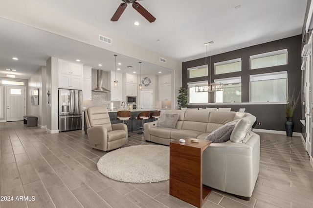 living room with ceiling fan with notable chandelier and light wood-type flooring