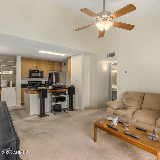 living room featuring light carpet, a high ceiling, and ceiling fan