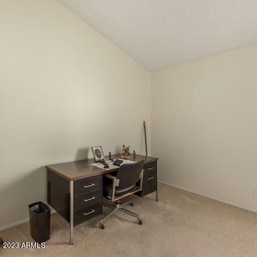 carpeted office space featuring vaulted ceiling