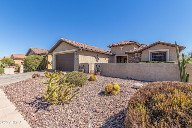 mediterranean / spanish-style home featuring a fenced front yard, driveway, an attached garage, and stucco siding