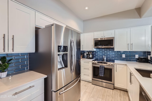 kitchen with backsplash, appliances with stainless steel finishes, white cabinetry, and light countertops