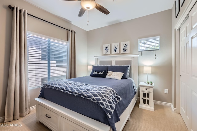 bedroom with a closet, ceiling fan, light carpet, and baseboards