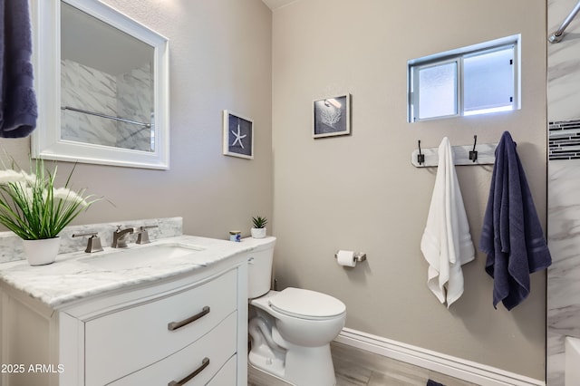 bathroom featuring vanity, toilet, wood finished floors, and baseboards