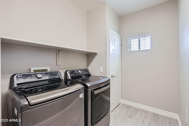 washroom with light wood-type flooring, baseboards, laundry area, and washer and clothes dryer