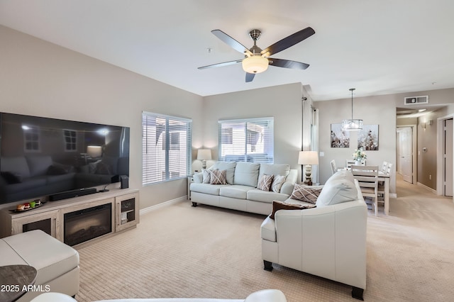 living area with visible vents, light colored carpet, baseboards, and ceiling fan