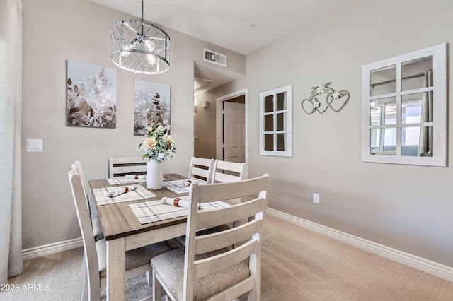 carpeted dining room featuring a notable chandelier, baseboards, and visible vents