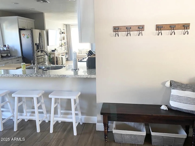 2100 N Normal Ave, Tempe, AZ 85288 - kitchen with stainless steel fridge with ice dispenser, light stone countertops, white cabinetry, a breakfast bar area, and a peninsula