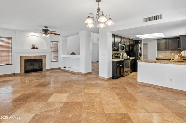 20809 N 1st Ave, Phoenix, AZ 85027 - kitchen with stainless steel appliances, backsplash, ceiling fan, a tiled fireplace, and pendant lighting