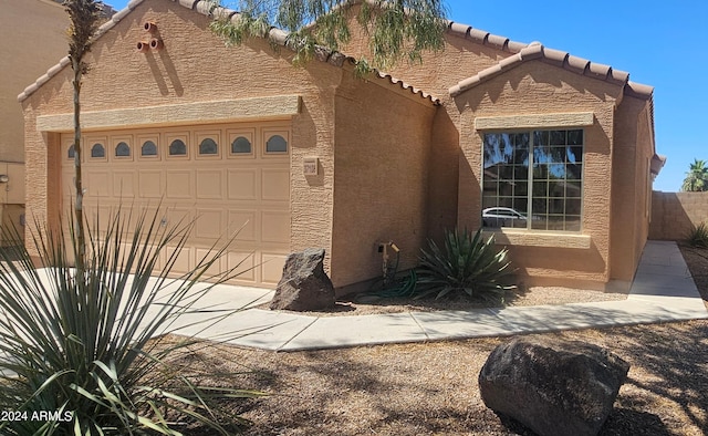 view of front of home with concrete driveway, a tiled roof, an attached garage, and stucco siding