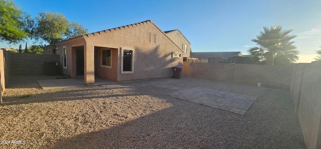 rear view of property with central AC unit, a patio area, a fenced backyard, and stucco siding