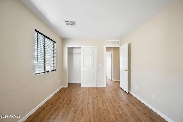 unfurnished bedroom featuring a closet, visible vents, light wood-style flooring, and baseboards