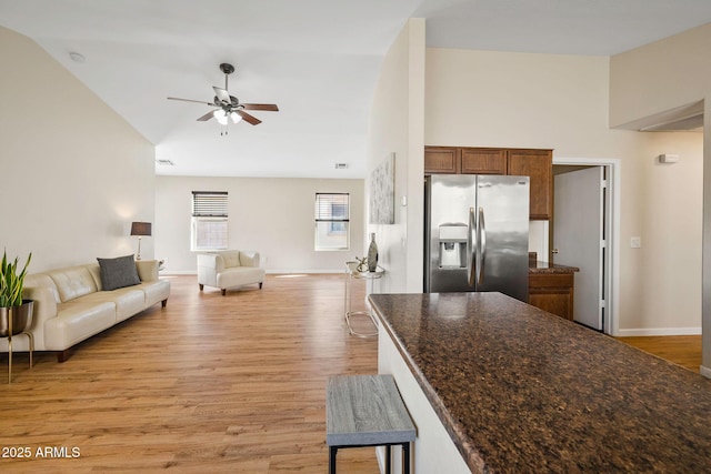 kitchen featuring brown cabinets, light wood-type flooring, open floor plan, and stainless steel fridge with ice dispenser