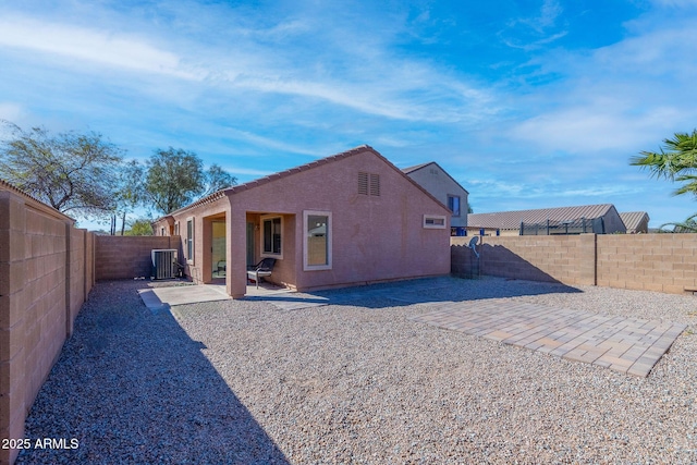 rear view of house with central AC unit, a patio area, a fenced backyard, and stucco siding