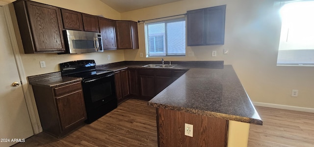 kitchen with dark countertops, black electric range oven, stainless steel microwave, a sink, and a peninsula