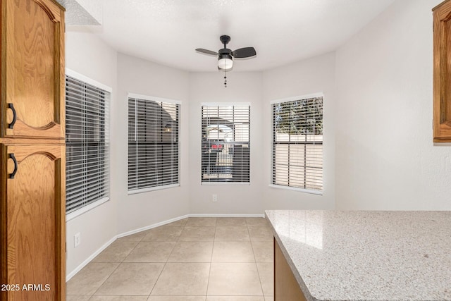 unfurnished dining area with ceiling fan and light tile patterned floors