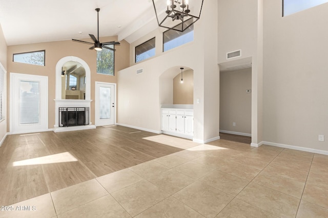 unfurnished living room featuring ceiling fan with notable chandelier, high vaulted ceiling, light tile patterned flooring, and beamed ceiling