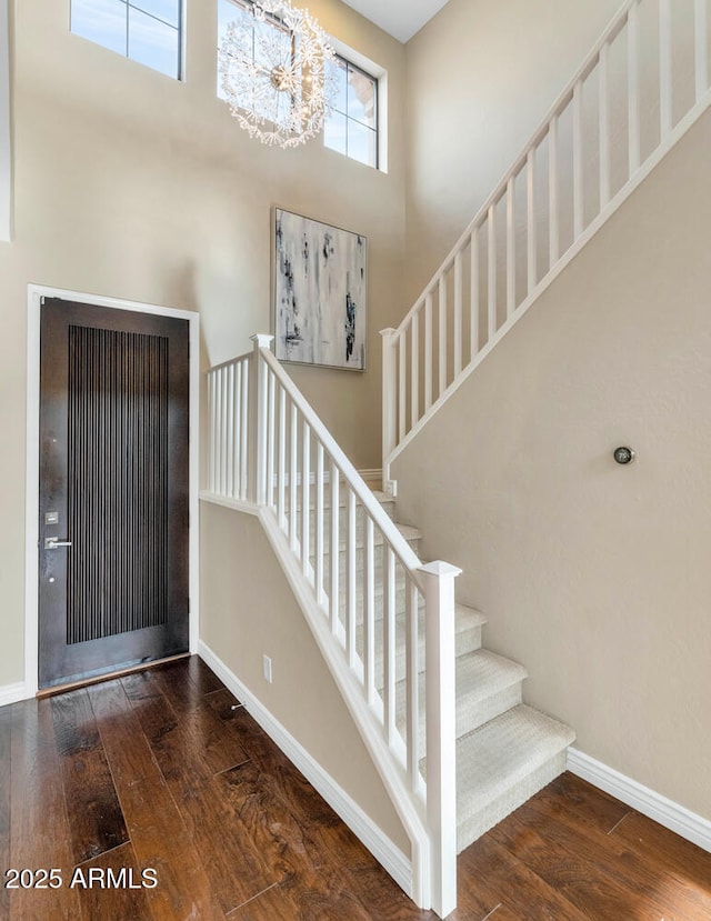 entryway with a high ceiling, stairway, wood-type flooring, and baseboards