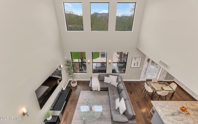 living room with dark wood-style floors, a high ceiling, and baseboards