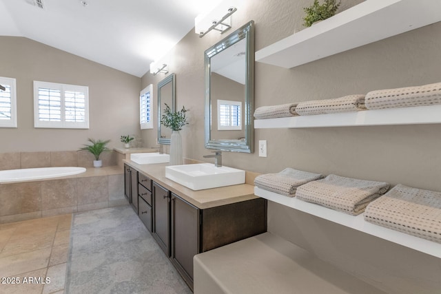 full bath with a garden tub, double vanity, lofted ceiling, a sink, and tile patterned flooring