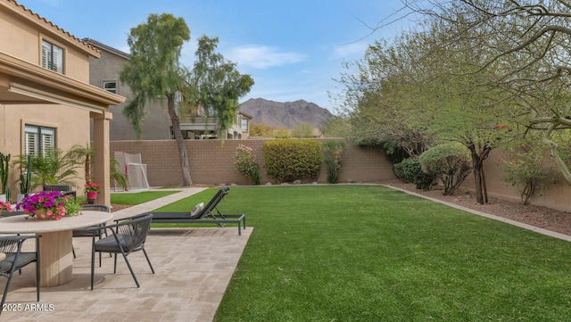 view of yard featuring a patio area, a fenced backyard, and a mountain view