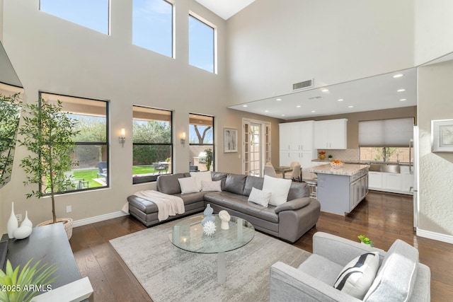 living area with plenty of natural light, dark wood finished floors, visible vents, and baseboards