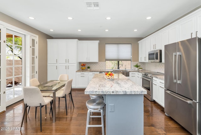 kitchen with stainless steel appliances, white cabinets, visible vents, and a kitchen island