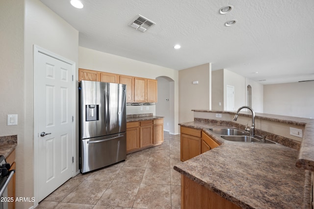 kitchen with visible vents, stainless steel refrigerator with ice dispenser, a sink, recessed lighting, and arched walkways
