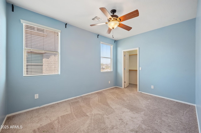 unfurnished bedroom with carpet, visible vents, baseboards, ceiling fan, and a spacious closet