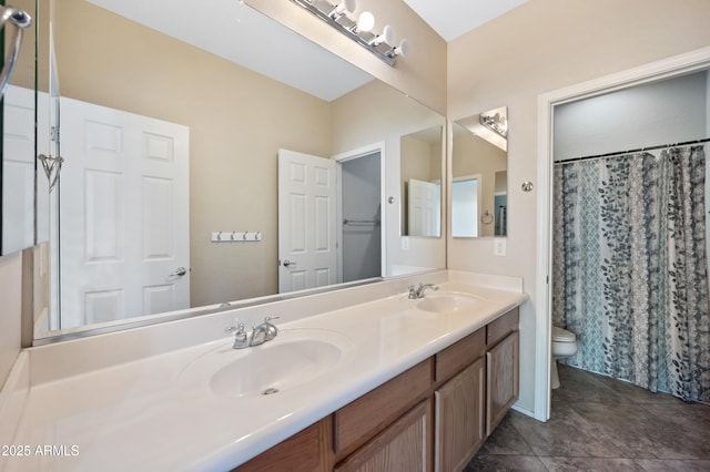 bathroom featuring double vanity, toilet, and a sink