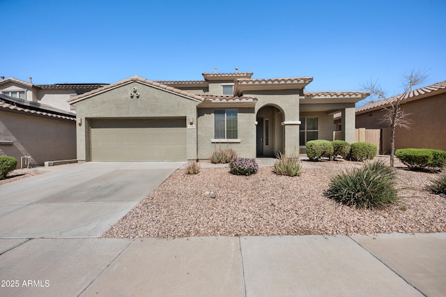 mediterranean / spanish-style home with stucco siding, a tiled roof, concrete driveway, and a garage