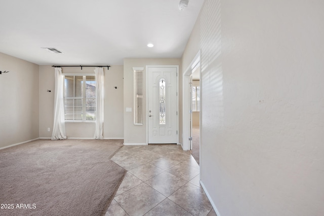 entryway featuring tile patterned flooring, visible vents, baseboards, and carpet floors