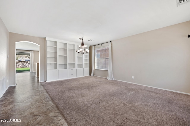 spare room featuring carpet, baseboards, visible vents, arched walkways, and a chandelier