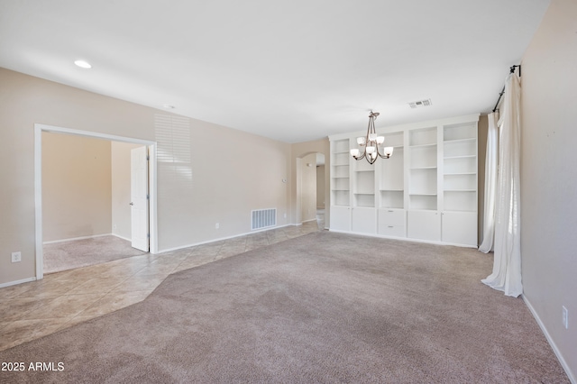 unfurnished living room featuring arched walkways, visible vents, an inviting chandelier, and carpet floors