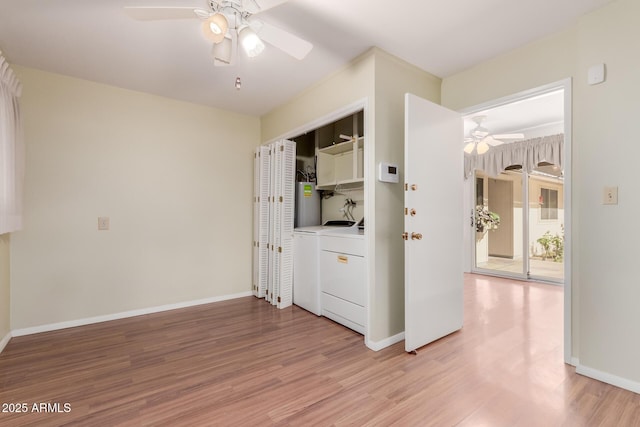 clothes washing area featuring cabinet space, baseboards, washer and clothes dryer, a ceiling fan, and light wood-style flooring