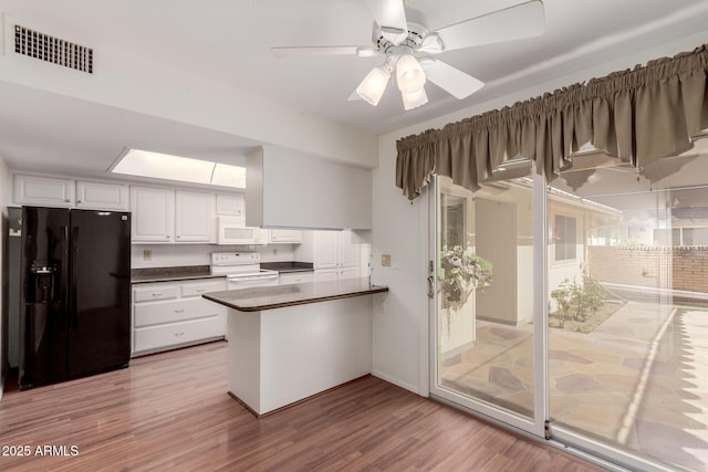 kitchen with a peninsula, white appliances, visible vents, white cabinets, and dark countertops