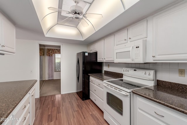 kitchen with light wood-type flooring, white appliances, a raised ceiling, and white cabinets