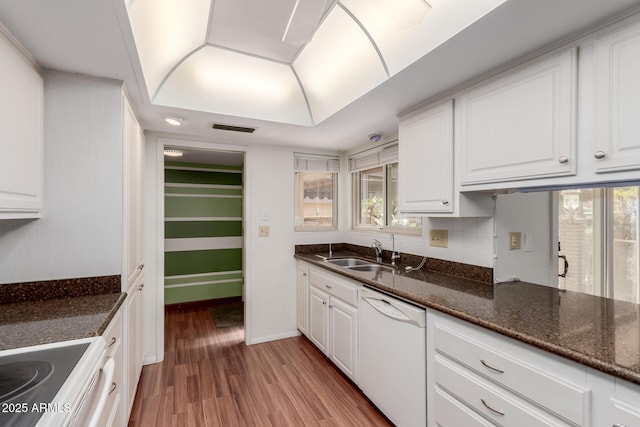 kitchen featuring visible vents, wood finished floors, white dishwasher, white cabinetry, and a sink